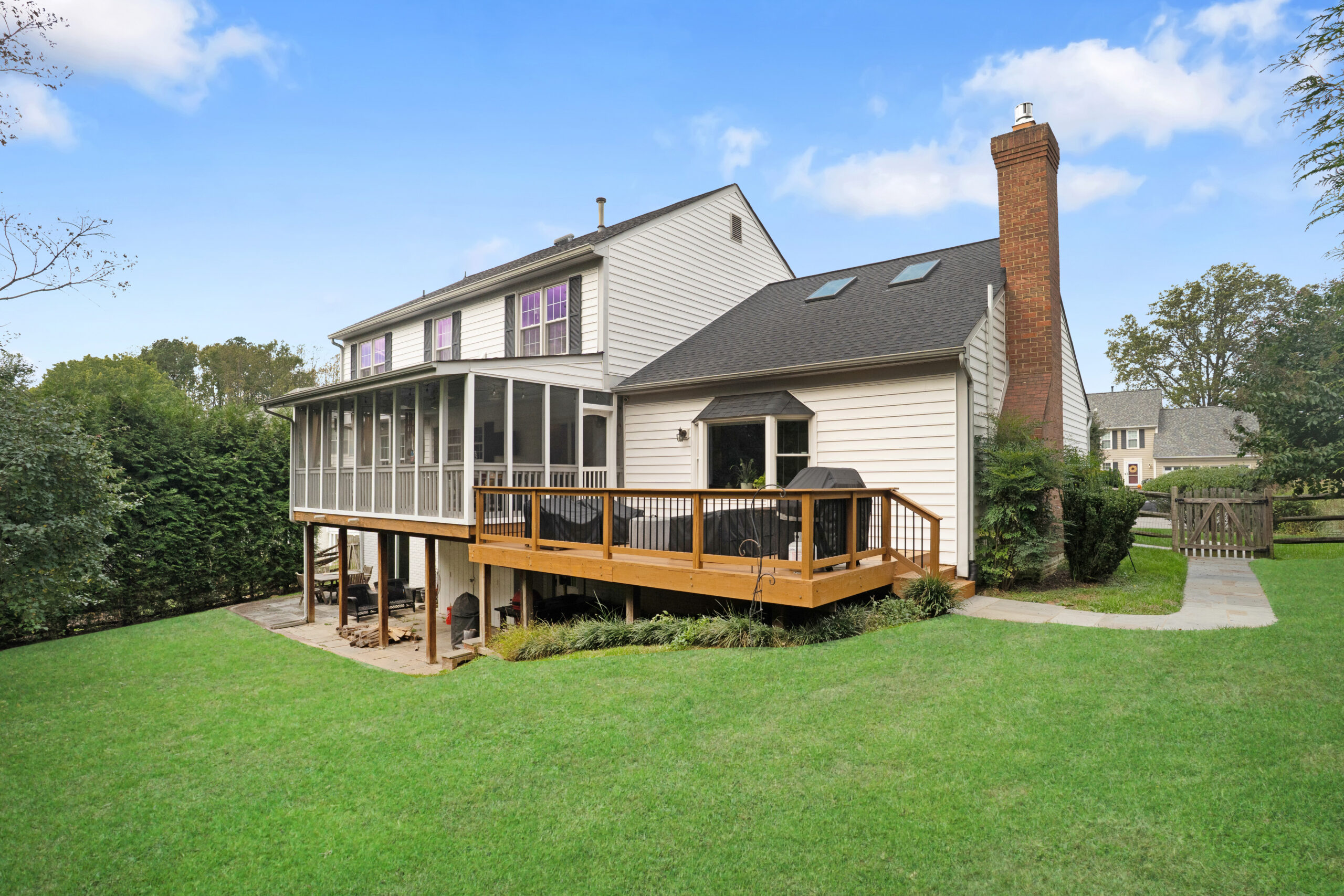 Rear exterior with deck and landscaped backyard